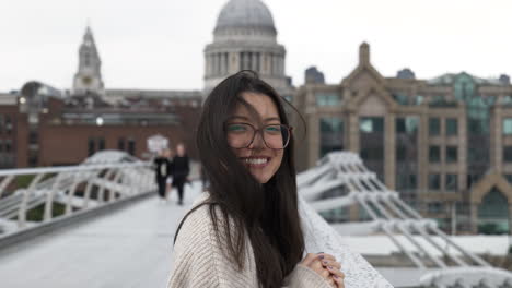 happy smiling tourist woman stood on millennium bridge, london in front of st pauls cathedral