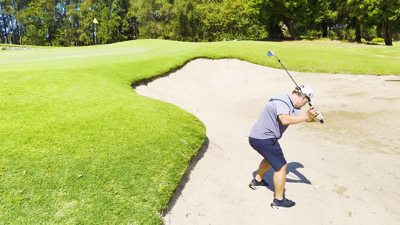 Golfer attempts a bunker shot on sunny day