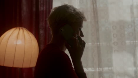 woman talking on phone by a window
