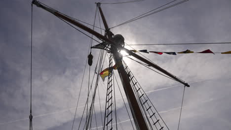 Sailboat-mast-against-the-sun-with-the-flags-blowing,-slow-motion