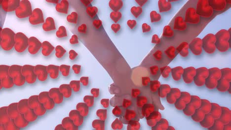 animation of hearts over hands of caucasian couple