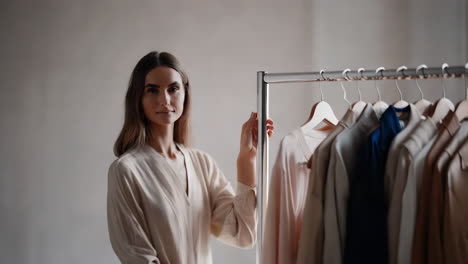 woman posing next to a clothing rack