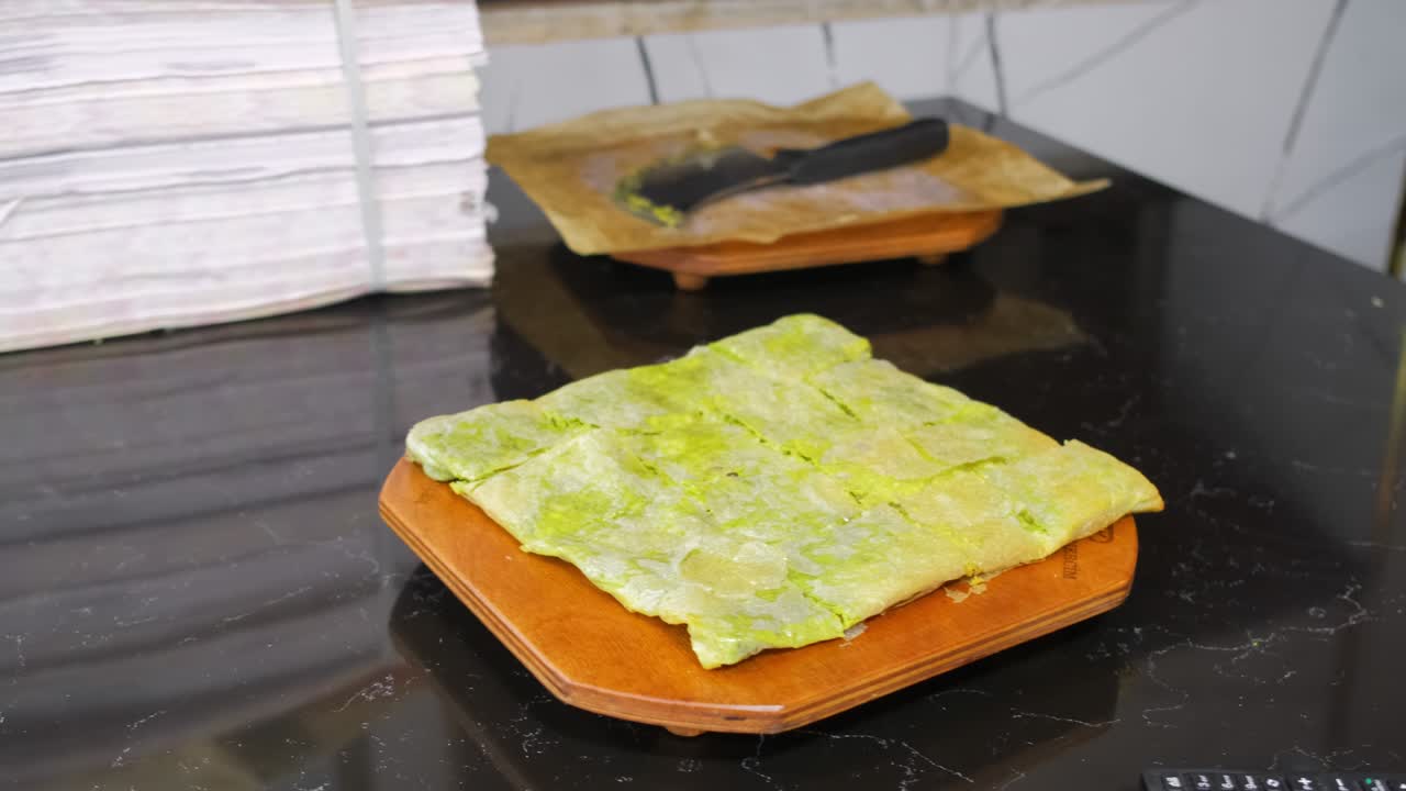el chef salpica el polvo de pistacho en la parte superior del postre katmer recién horneado