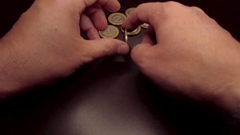 moneda de 10 pesos girando a mano sobre una mesa de madera