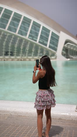 woman taking photos near a fountain and modern architecture
