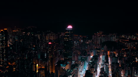 drone shot, traveling to the left, of a big city during the night with a landmark business building in the middle. the streets are busy and give the shot a cyberpunk atmosphere.