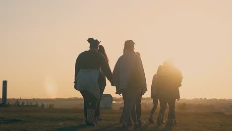 young friends walk along meadow with dry grass slow motion