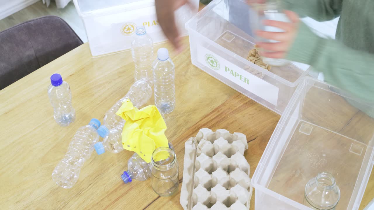 Prompted by bin labels, Diverse parent and child sorting bottles, jars into bins on wooden table