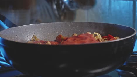 vertiendo salsa de tomate en un wok con carne y verduras para tortillas mexicanas y mezclándolo todo con una cuchara de madera