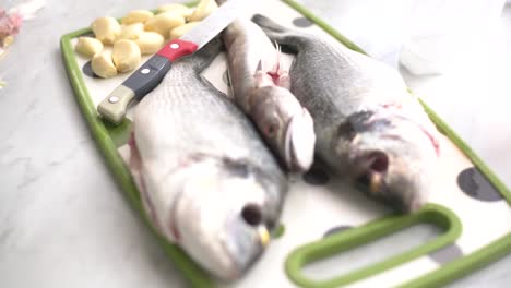 hand peeling garlic next to a sea bream and a whiting on the work surface