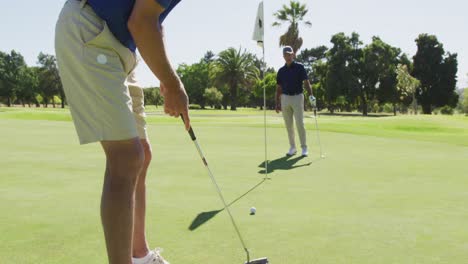 Two-caucasian-senior-man-practicing-golf-at-golf-course-on-a-bright-sunny-day