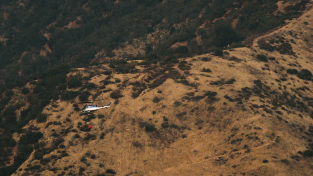 Helicopter with Water Bucket Over Dry Hills