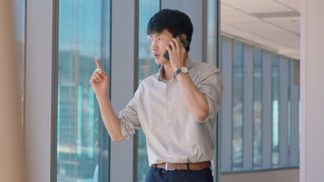 asian businessman using smartphone chatting to client financial advisor negotiating business deal corporate sales executive sharing expert advice having phone call in office looking out window