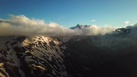 Aerial-view-of-austrian-mountains-snowy-peaks-reaching-the-clouds