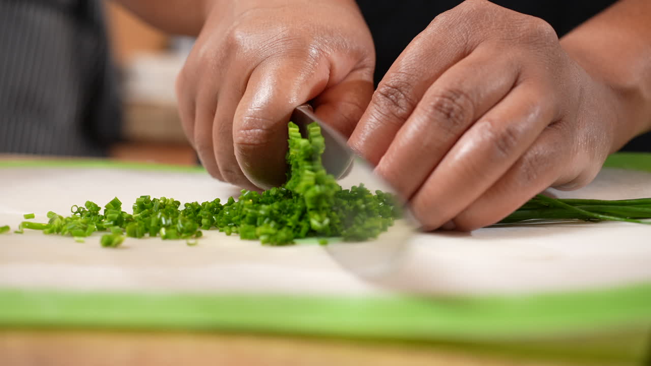 Chopping green chives - an ingredient for a homemade savory recipe - isolated in slow motion
