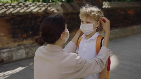 mother putting face mask on child before school
