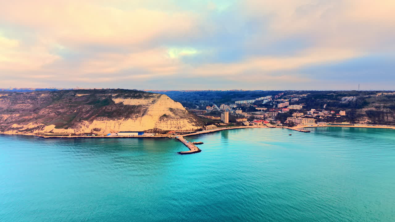 Vista aerea di una baia costiera con un molo in cemento, un porto ed edifici residenziali sulla costa. Veduta dall'alto di una baia e di una città costiera.