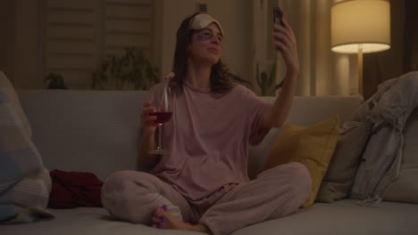 woman relaxing at home with wine and smartphone