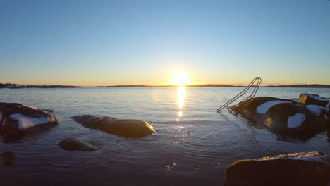 4k shot of metal stairs going down in the cold water on a winter dat during sunset at gothenburg, sweden