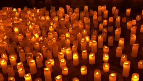 rows of flickering candles create warm spiritual ambiance in darkness