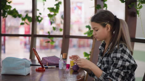joven aplica cuidadosamente el maquillaje en la mano antes de usar esponja para mezclarse en la cara, productos de belleza, espejo y pinceles dispuestos en una mesa de madera resaltan el cuidado personal y el arte del maquillaje