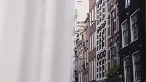 outdoor string light bulbs hanging between the apartment buildings at a street in amsterdam, netherlands