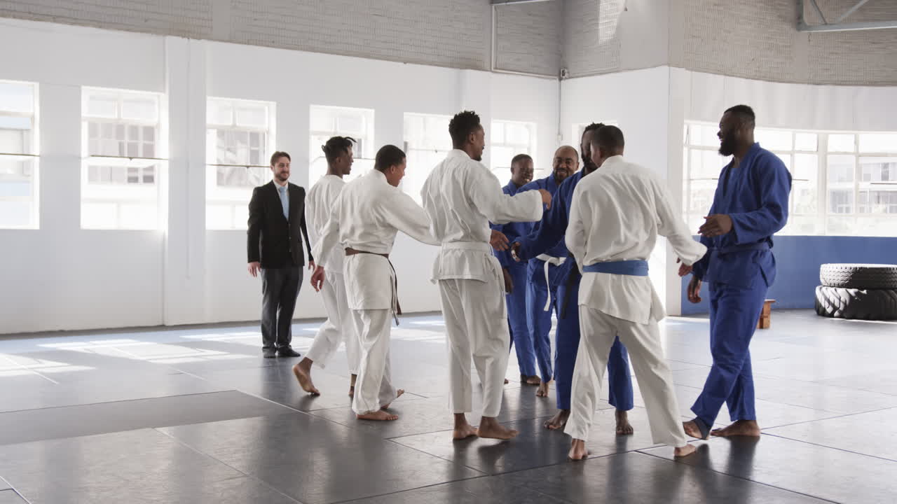 Judo practitioners in dojo gathering for training, wearing traditional uniforms