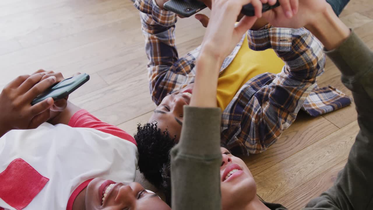 Video of happy diverse male teenage friends using smartphones, slow motion