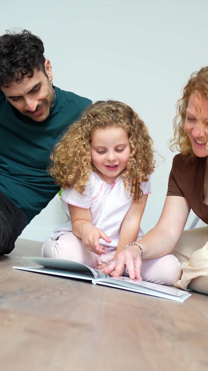 Famiglia felice che legge un libro insieme sul pavimento