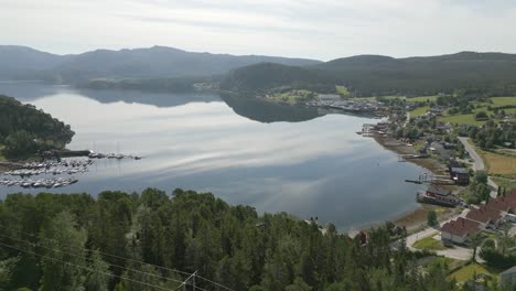 Epic-nature-scene-of-calm-Norwegian-lake-surrounded-by-lush-forest,-aerial