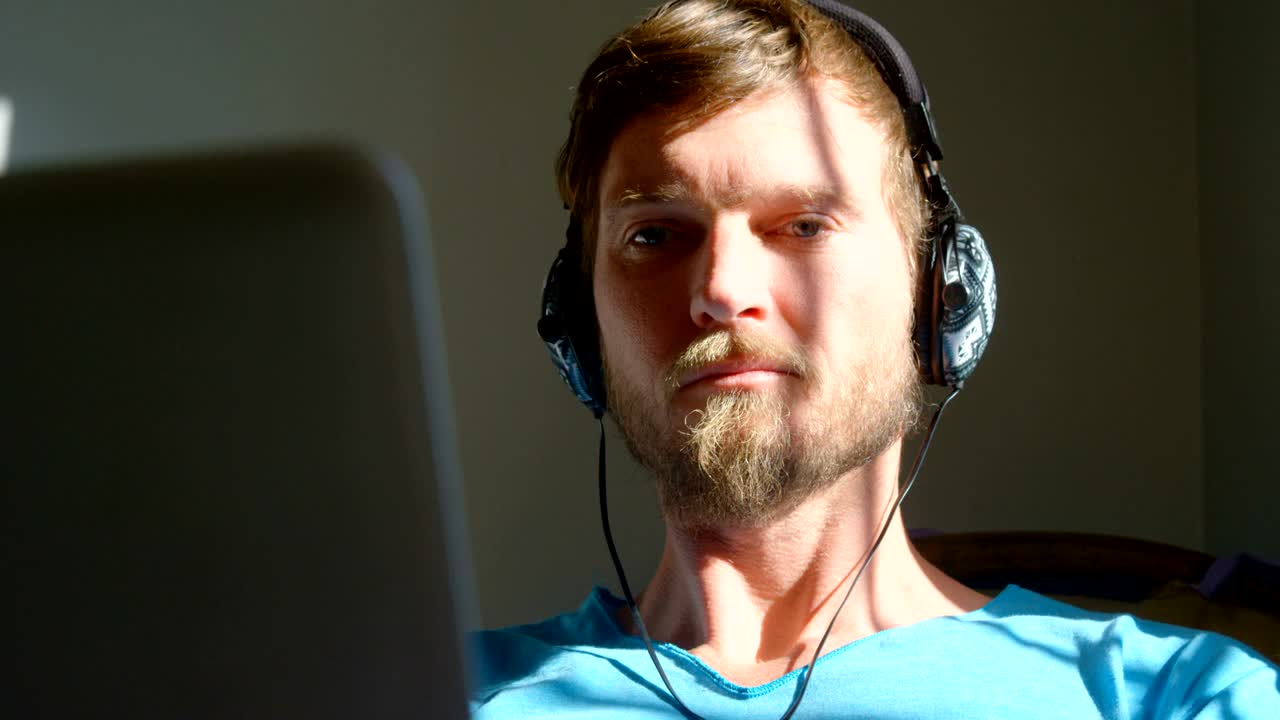 hombre usando portátil con auriculares 4k