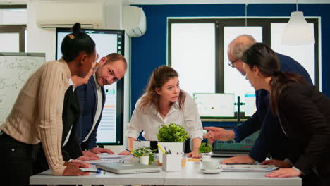 Diverse-team-of-workers-talking,-looking-at-documents-and-analyzing-graphs