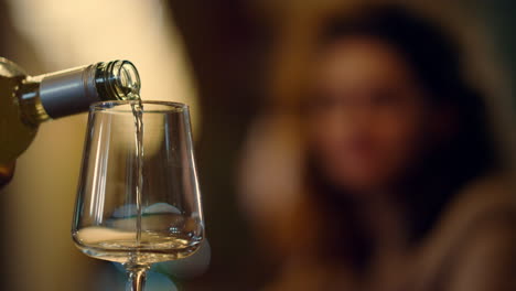 Unknown-bartender-pouring-wine-from-bottle.-Blurred-woman-taking-glass-indoors.