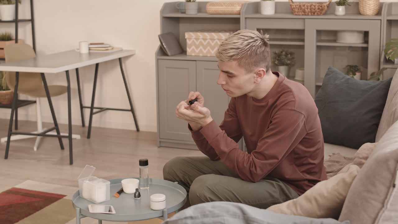 Young Man with Stylish Hairstyle Applying Nail Polish