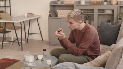 young man with stylish hairstyle applying nail polish