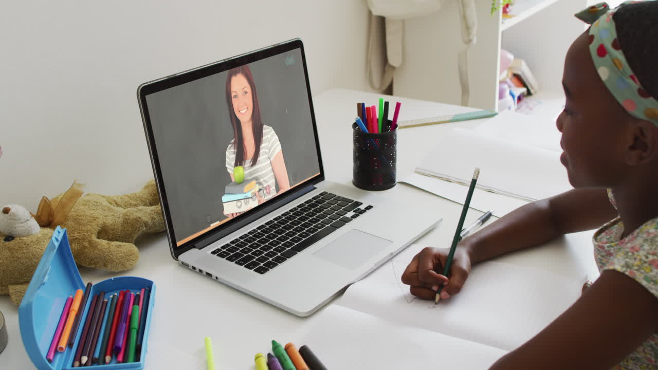 African american girl having a video call on laptop while doing homework at home