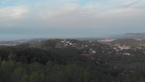 Forward-drone-reveals-valley-housing-estate-during-sunrise-within-mountains