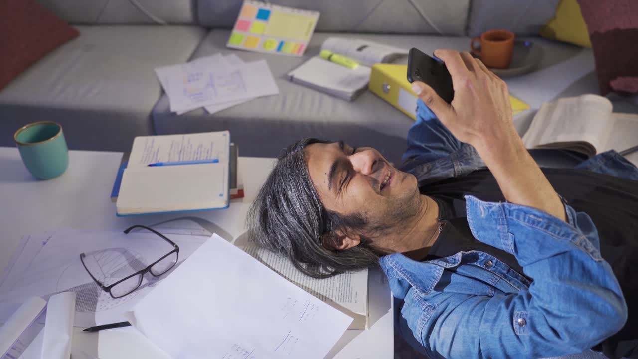 hombre perezoso mirando el teléfono en casa y sonriendo.