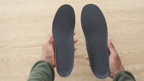 person holding a pair of shoe insoles