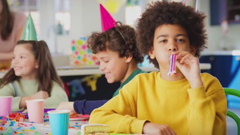 boy with birthday cake and party blower at party with parents and friends at home