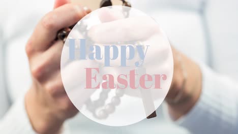 Animation-of-happy-easter-text-over-caucasian-woman-praying-with-rosary