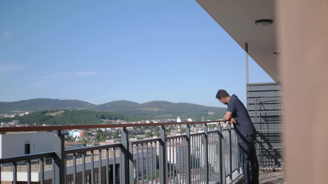 Uomo in piedi sul balcone che guarda il panorama della città