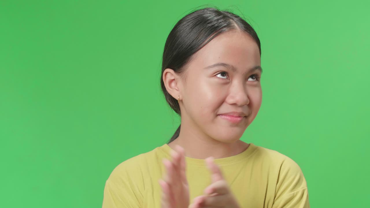 Close Up Of Young Asian Kid Girl And Emotionally Flipping Something While Clapping Hands In The Green Screen Studio