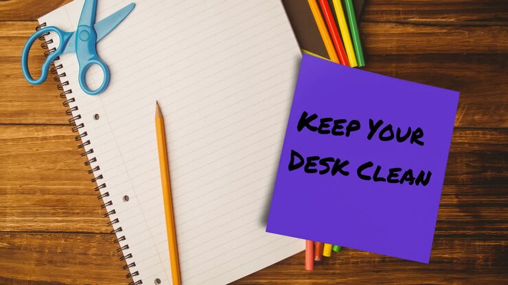 Animazione del testo 'mantieni la tua scrivania pulita' su una nota adesiva sopra un quaderno e delle matite su una scrivania.