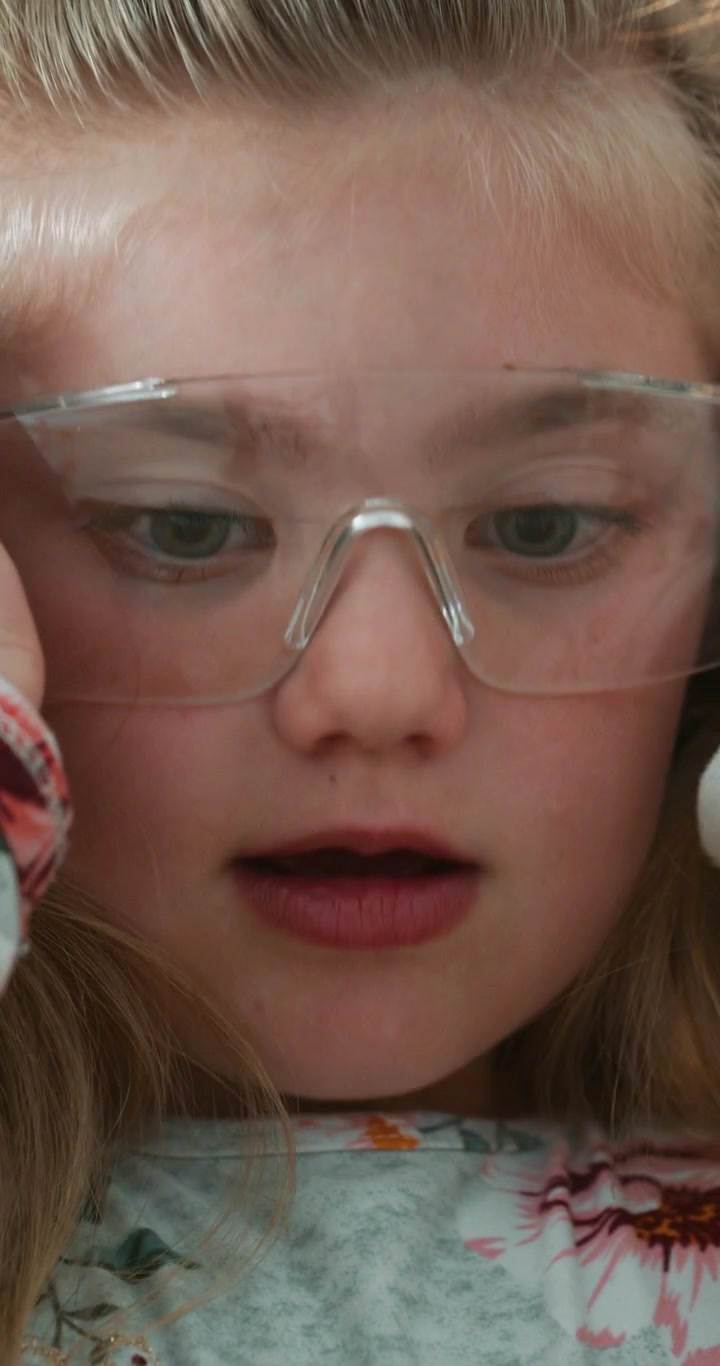 Giovane ragazza con occhiali di sicurezza che conduce un esperimento scientifico