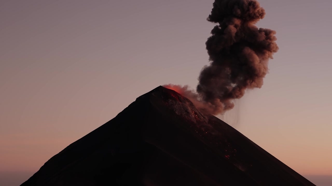 Eruzione esplosiva di lava incandescente dal Vulcano Fuego sopra la vetta al tramonto, Guatemala.