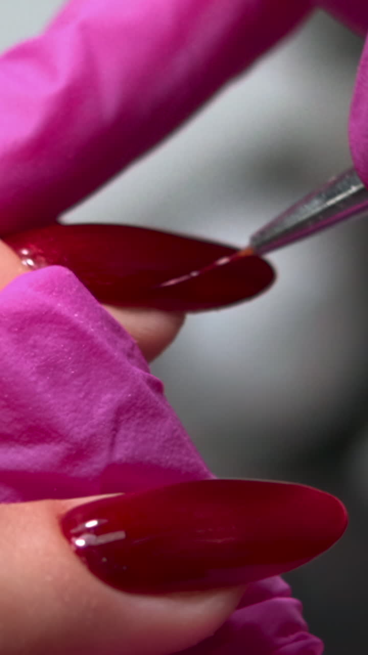 Close-up of Manicurist Applying Top Coat to Red Nails
