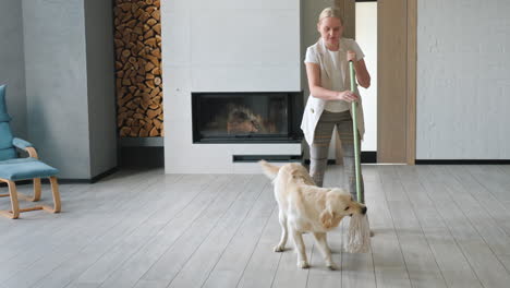 woman and golden retriever playing with mop in living room