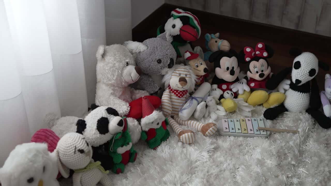 Group of plush toys and baby xylophone arranged on a soft white rug in a cozy corner