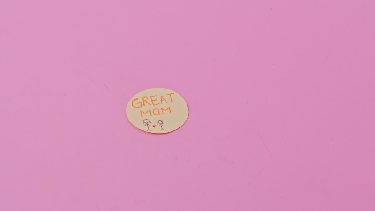 Handcrafted "Great Mom" message with red paper heart on pink background for Mother's Day concepts